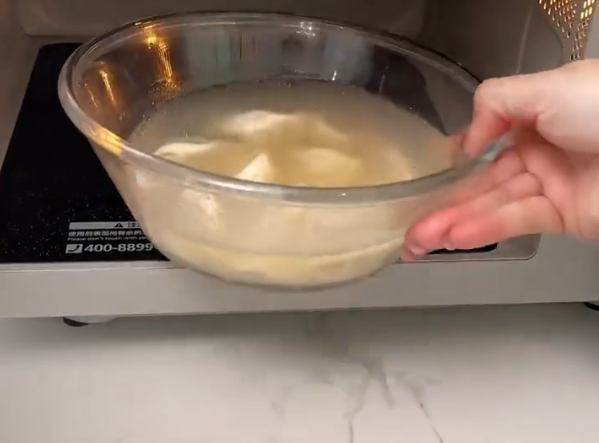 女生在公司内用微波炉加热速冻饺子