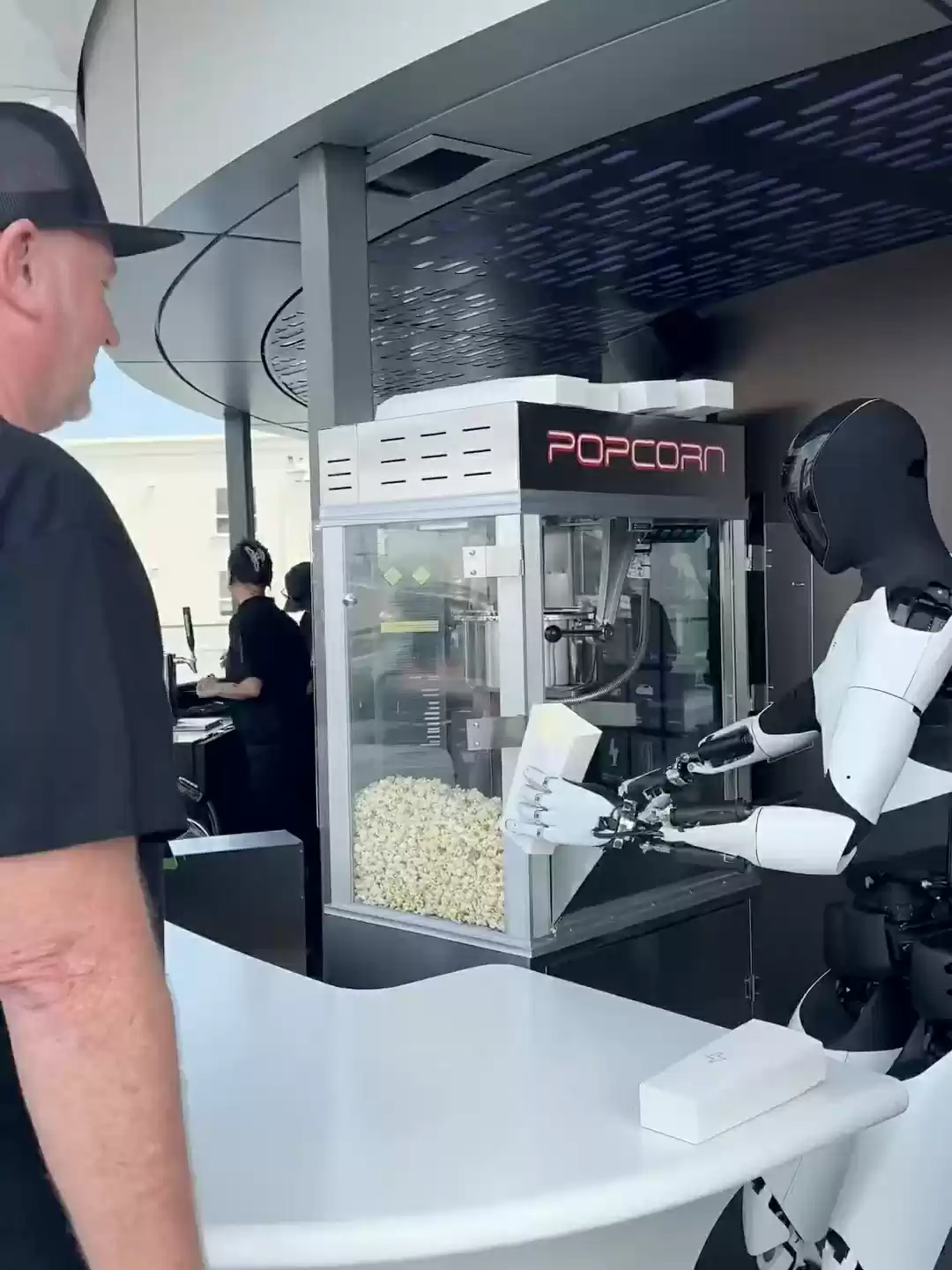特斯拉 TeslaAI 官方微博发布首条视频:人形机器人卖爆米花,还可与顾客合影互动