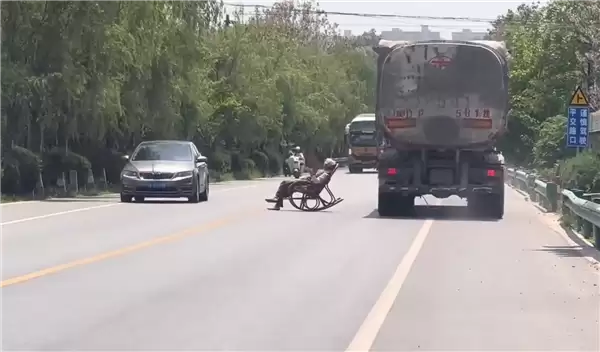 大爷马路中间手拿折扇躺摇椅上晒太阳 过往车辆纷纷减速避让